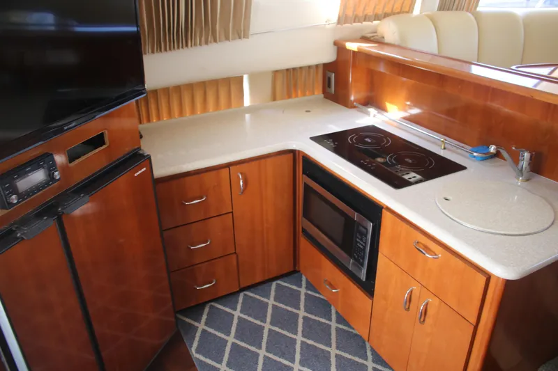 Slide: The Image of 2004 Carver 360 Sport Sedan kitchen with stove, microwave, and wooden cabinetry. - 13