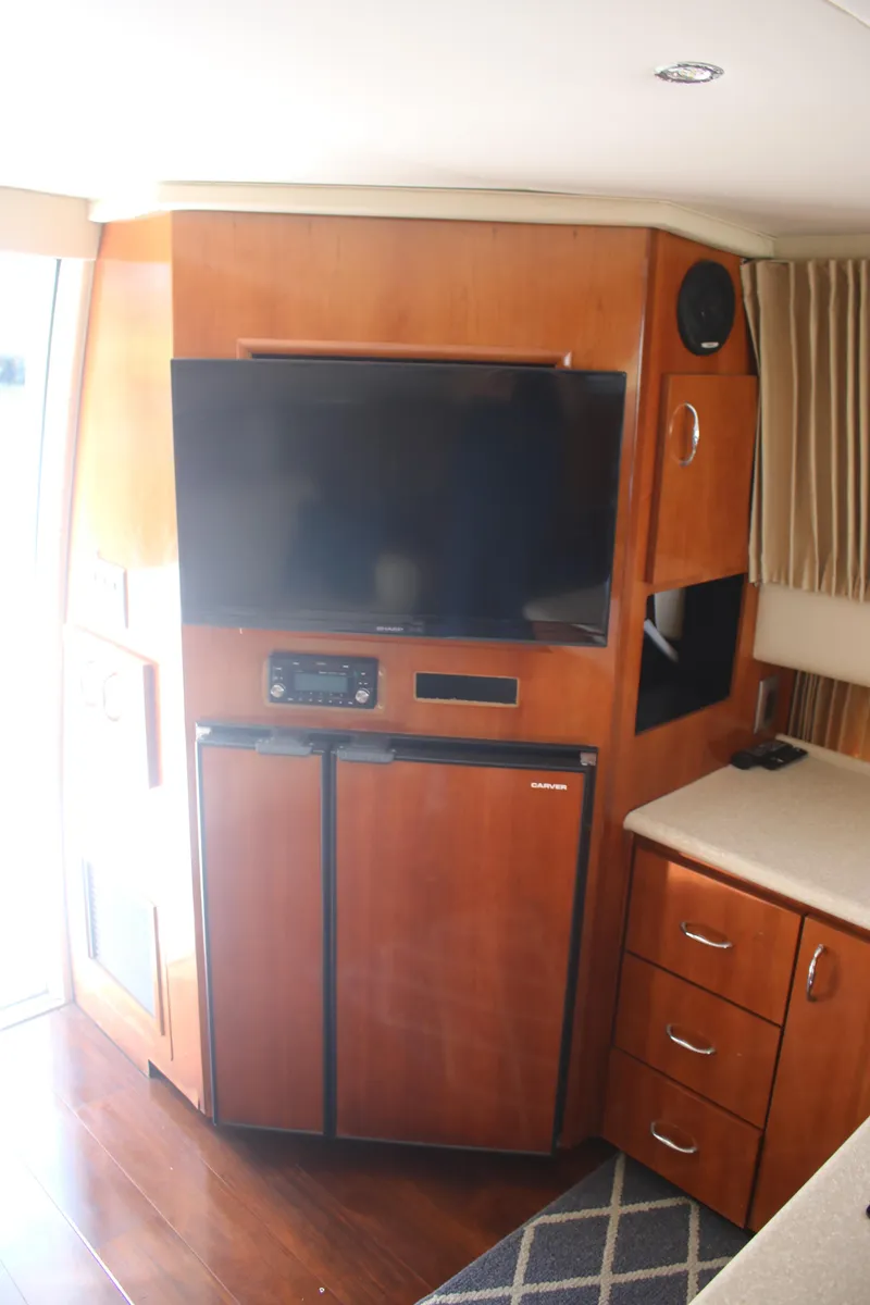 Slide: The Image of 2004 Carver 360 Sport Sedan interior with TV, fridge, and wooden cabinetry. - 14