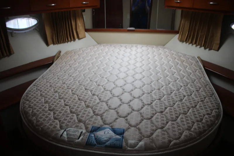 Slide: The Image of 2004 Carver 360 Sport Sedan interior with a large, cushioned bed and wooden cabinetry. - 15