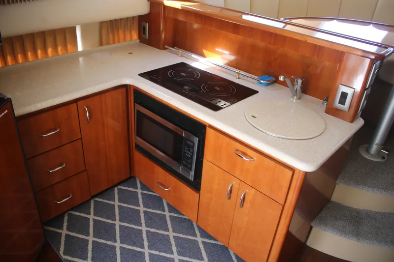 Slide: The Image of 2004 Carver 360 Sport Sedan kitchen with stove, microwave, and wooden cabinetry. - 19