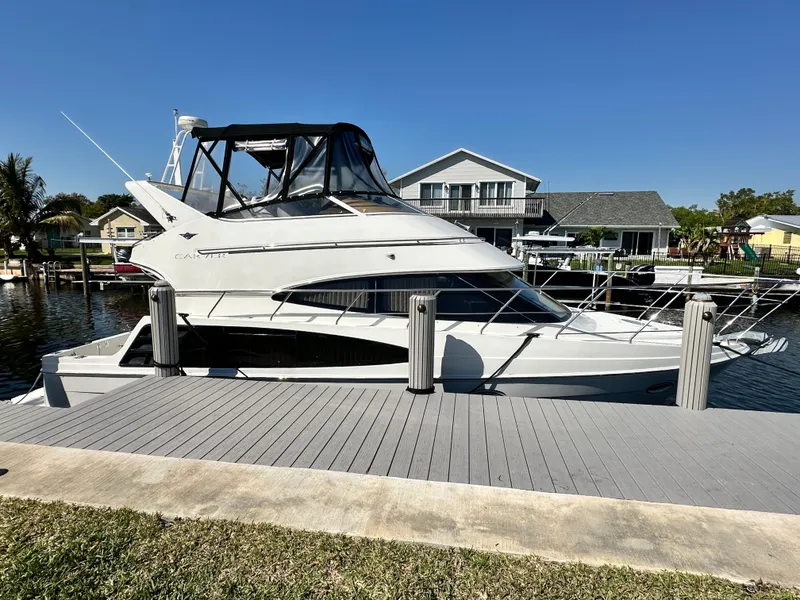 Slide: The Image of 2004 Carver 360 Sport Sedan docked by waterfront homes under clear blue sky. - 4
