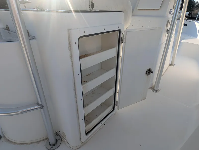 Slide: The Image of 2003 Pro-Line 22 Sport boat storage compartment with open shelves, sunlight reflecting on white surface. - 19