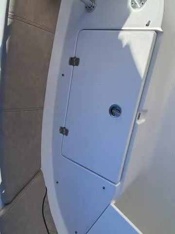 Slide: The Image of 2020 Sportsman Open 242 boat storage compartment with secure latch and hinges. - 12