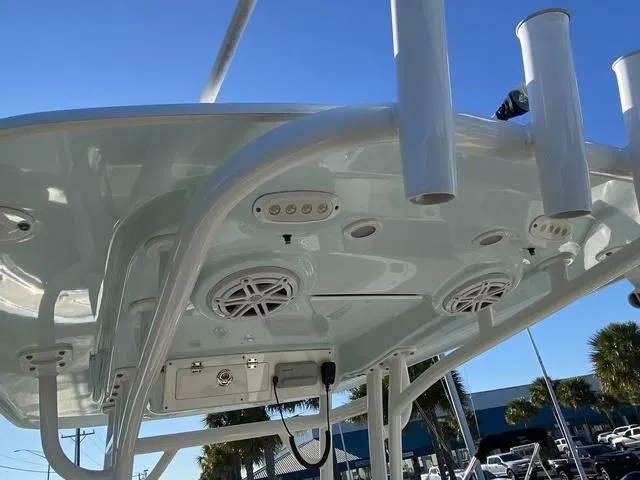 Slide: The Image of 2020 Sportsman Open 242 boat T-top with speakers and rod holders under clear blue sky. - 40