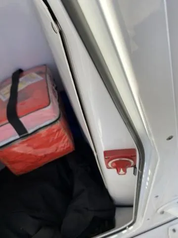 Slide: The Image of 2020 Sportsman Open 242 storage compartment with red safety switch and orange bag. - 45