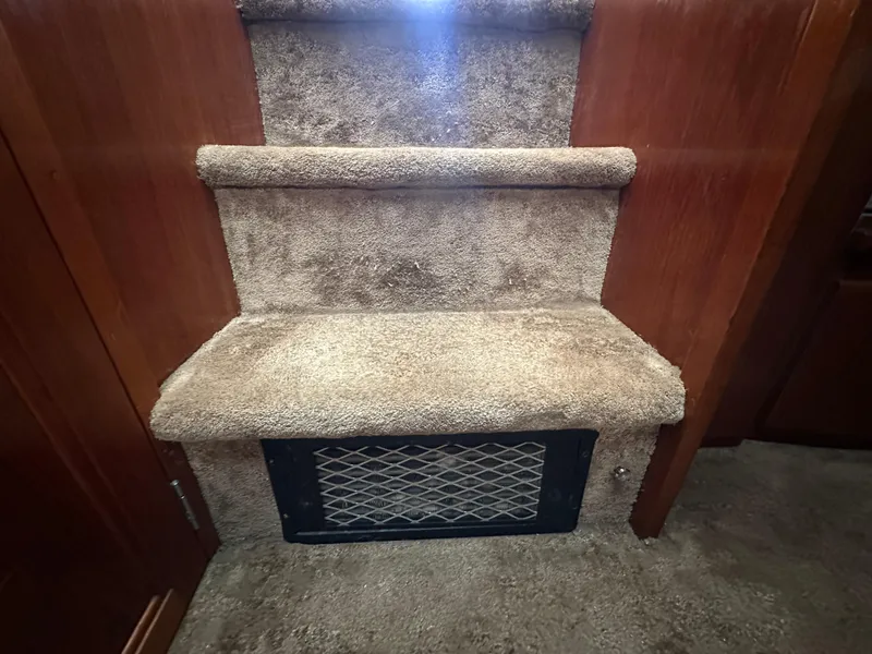 Slide: The Image of Carpeted stairs inside a 1994 Carver 370 Voyager boat, featuring wooden paneling. - 42