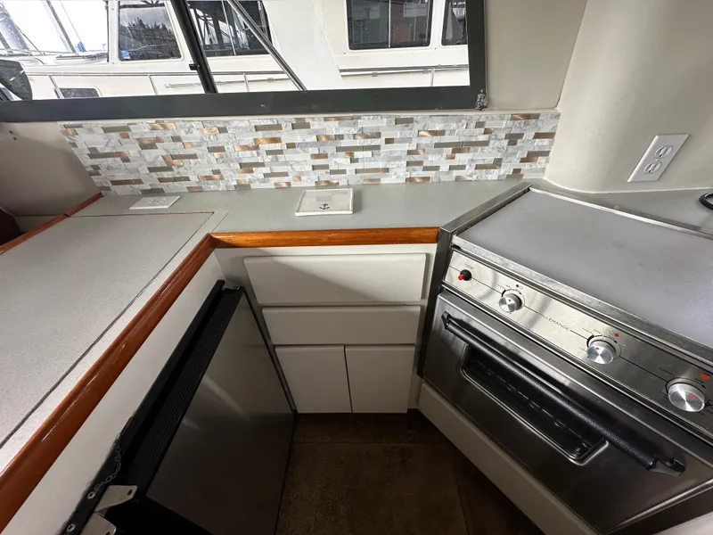 Slide: The Image of 1994 Carver 370 Voyager kitchen with stove, cabinets, and mosaic backsplash. - 45