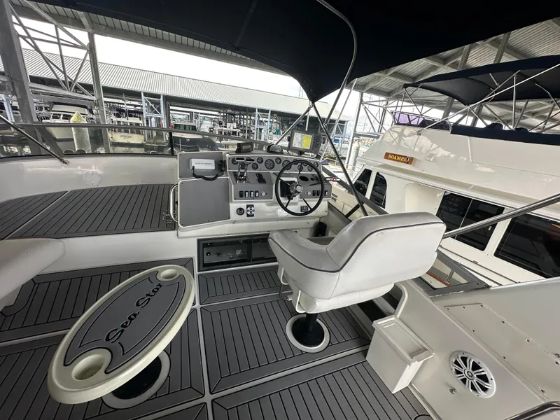 Slide: The Image of 1994 Carver 370 Voyager boat helm with steering wheel, control panel, and seating under canopy. - 11