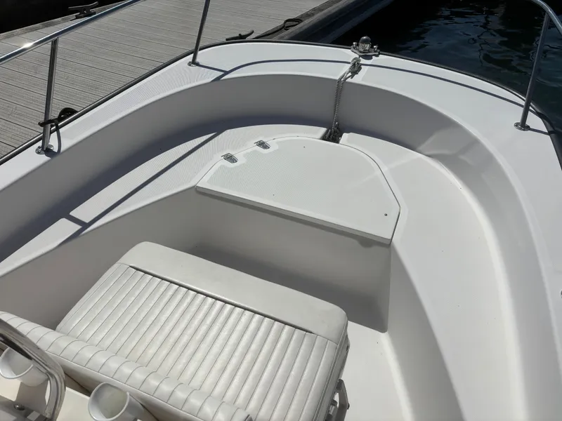 Slide: The Image of 2004 Boston Whaler 170 Montauk boat interior with seating and storage, docked by the water. - 3