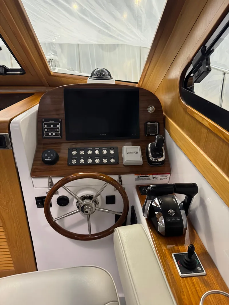 Slide: The Image of 2022 True North 34 Outboard Express helm with wooden accents and modern controls. - 13