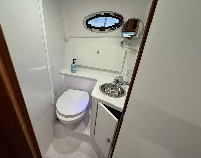 Slide: The Image of 2022 True North 34 Outboard Express bathroom with toilet, sink, and porthole window. - 18