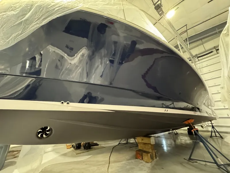Slide: The Image of 2022 True North 34 Outboard Express boat in a workshop, partially covered, on supports. - 24