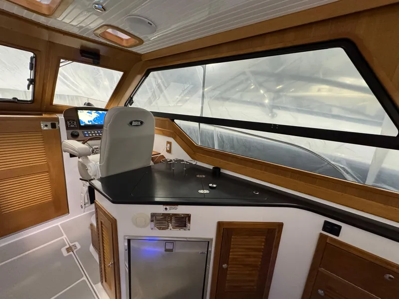 Slide: The Image of 2022 True North 34 Outboard Express interior with helm, navigation system, and wooden cabinetry. - 6