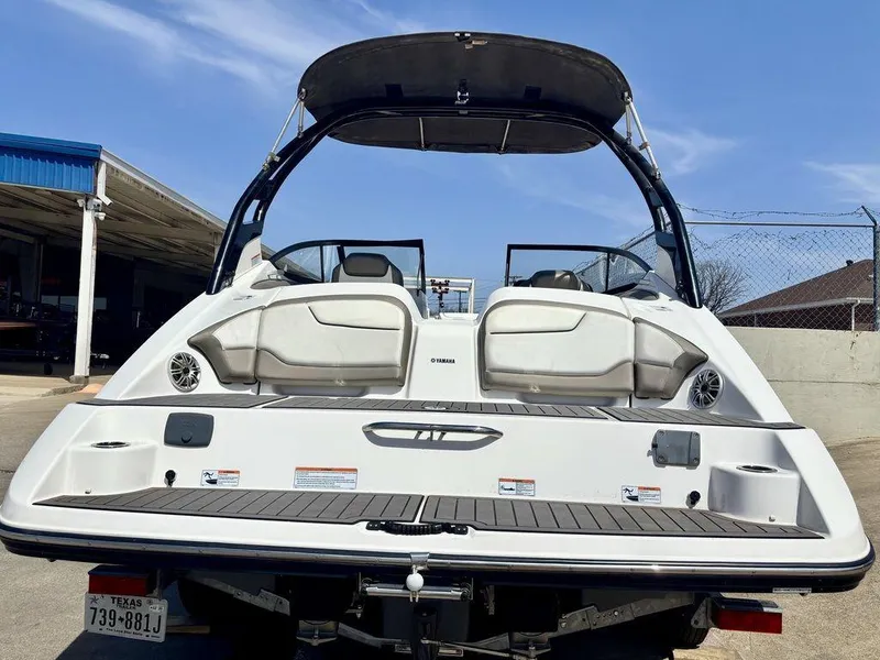 Slide: The Image of 2017 Yamaha Boats 212 Limited S, rear view, white exterior, docked under blue sky. - 3