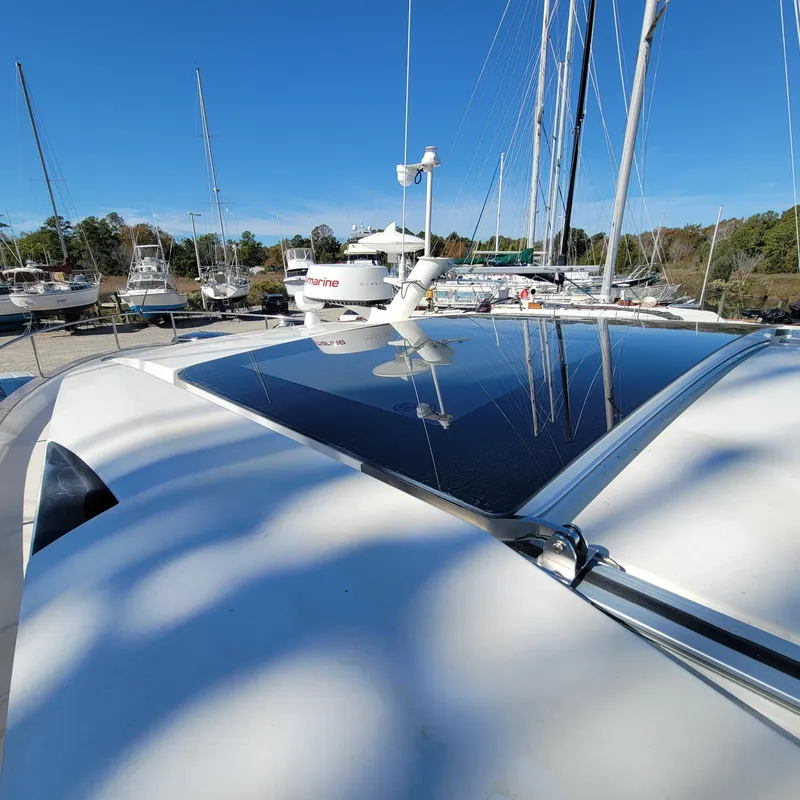 Slide: The Image of 2022 Greenline 40 Hybrid yacht with solar panels, docked among sailboats under clear blue sky. - 32