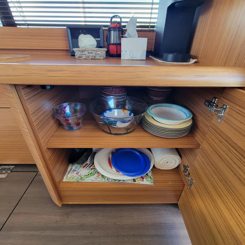 Slide: The Image of Wooden cabinet with dishes and bowls inside a 2022 Greenline 40 Hybrid yacht kitchen. - 40