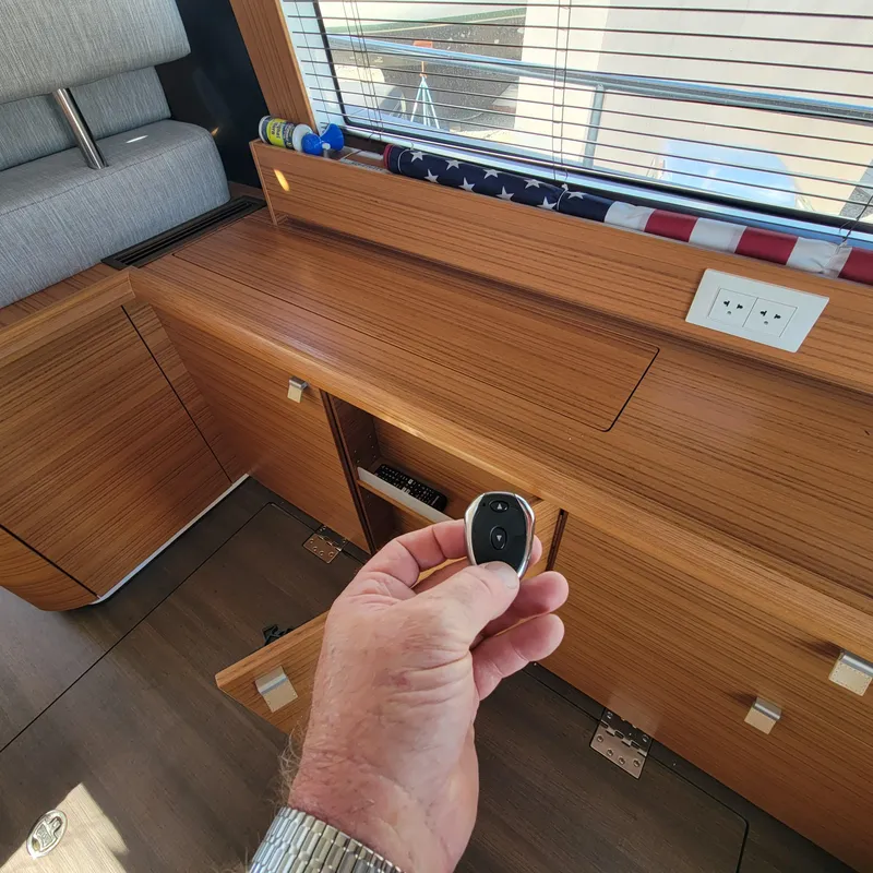 Slide: The Image of Hand holding remote inside 2022 Greenline 40 Hybrid yacht, showcasing wooden interior and outlets. - 41
