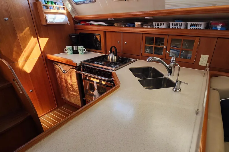 Slide: The Image of 2005 Hunter 41 Deck Salon kitchen with stove, sink, and wooden cabinetry. - 20
