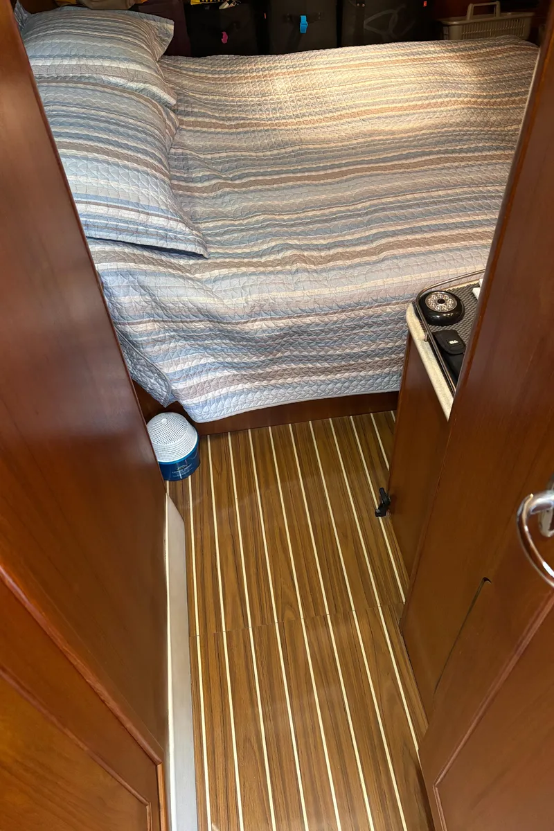 Slide: The Image of 2005 Hunter 41 Deck Salon interior with striped bedding and wooden flooring. - 26