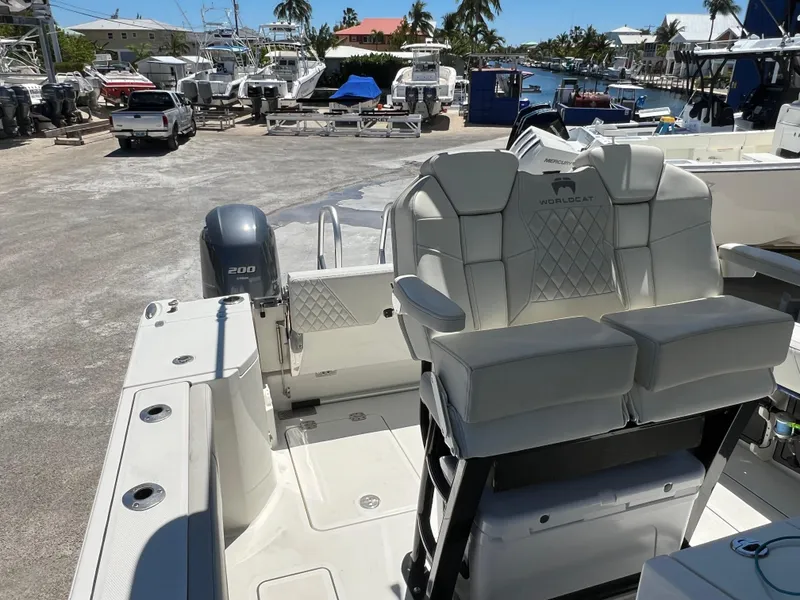 Slide: The Image of 2024 World Cat 260 CC-X boat interior with seating and outboard motor in marina setting. - 16