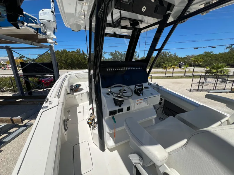 Slide: The Image of 2024 World Cat 260 CC-X boat interior with helm, steering wheel, and seating under clear blue sky. - 21