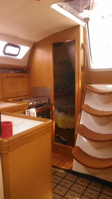 Slide: The Image of Interior of 2010 Jeanneau Sun Odyssey 36i sailboat, featuring wooden cabinetry and compact kitchen area. - 16