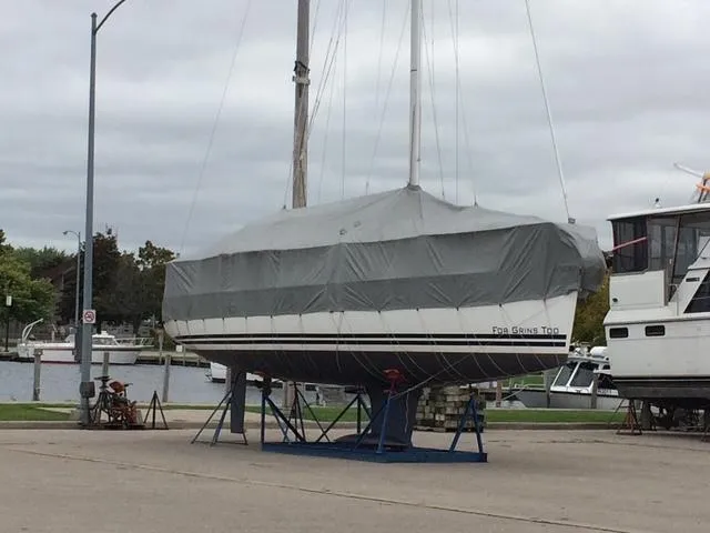 Slide: The Image of Jeanneau Sun Odyssey 36i sailboat, 2010 model, covered and docked on land near a marina. - 2