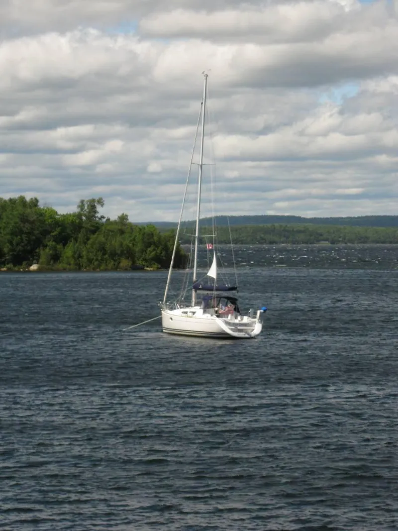 Slide: The Image of 2010 Jeanneau Sun Odyssey 36i sailboat on a serene lake under cloudy skies. - 3
