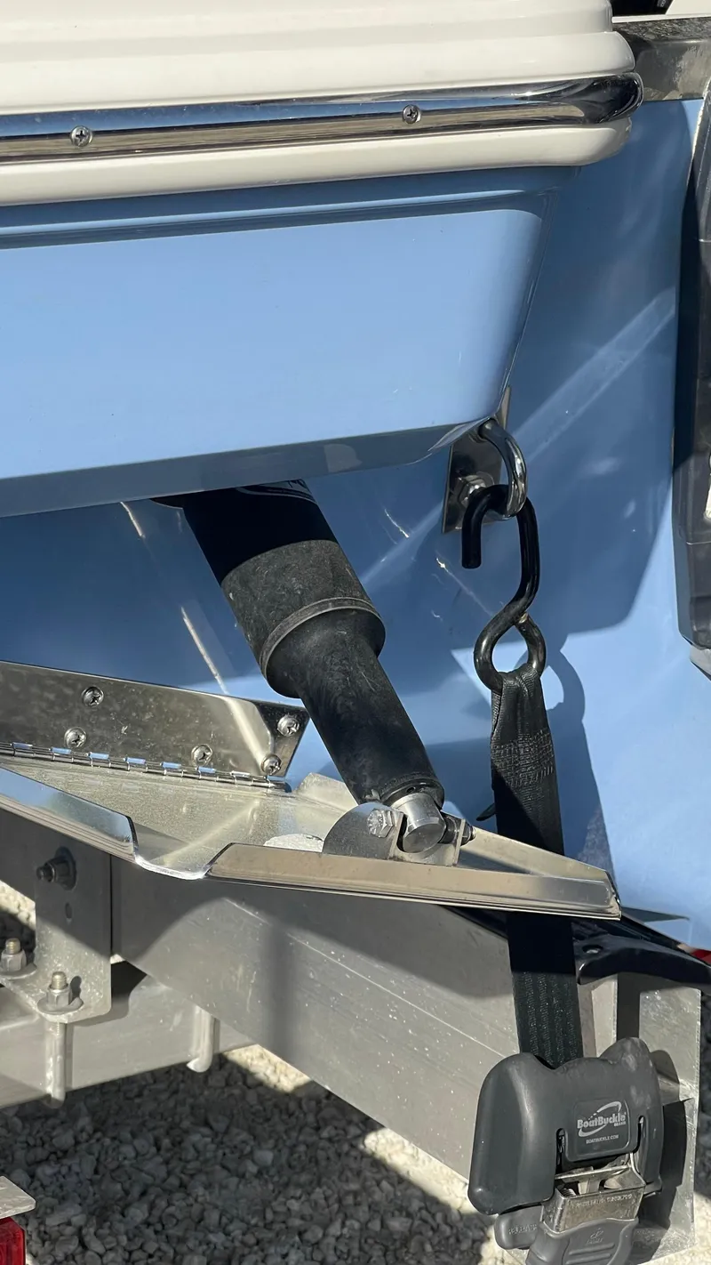 Slide: The Image of 2023 Robalo R272 Center Console boat trailer detail with blue hull and secure strap. - 21