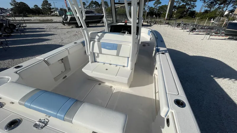 Slide: The Image of 2023 Robalo R272 Center Console boat interior with seating and console, parked outdoors. - 22