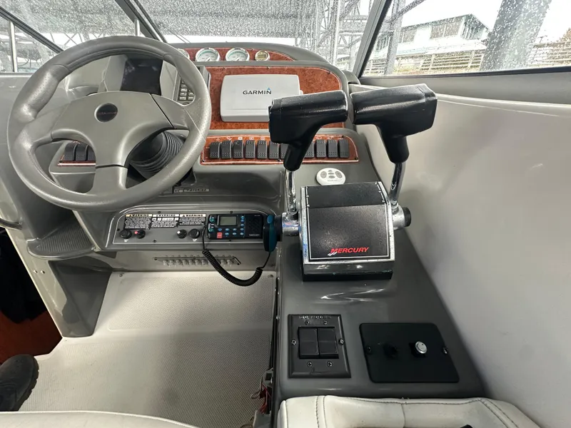 Slide: The Image of 2005 Bayliner 305 boat cockpit with steering wheel, Mercury throttle controls, and Garmin navigation system. - 14