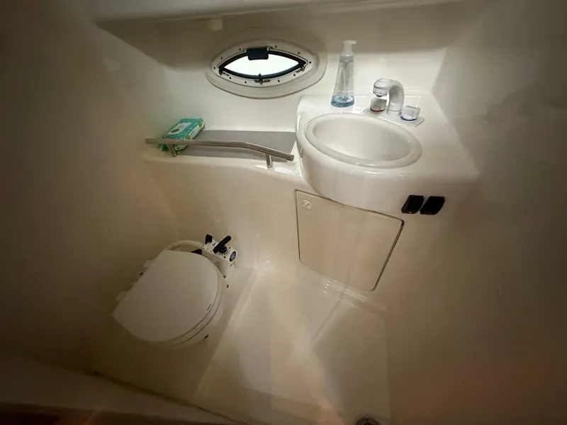 Slide: The Image of 2005 Bayliner 305 boat bathroom with toilet, sink, and porthole window. - 17