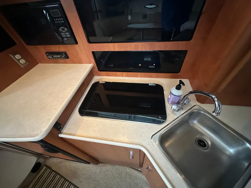 Slide: The Image of 2005 Bayliner 305 boat kitchen with sink, stove, and countertop. - 23