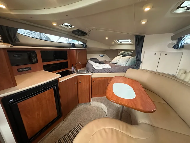 Slide: The Image of 2005 Bayliner 305 cabin interior with kitchenette, seating, and sleeping area. - 26