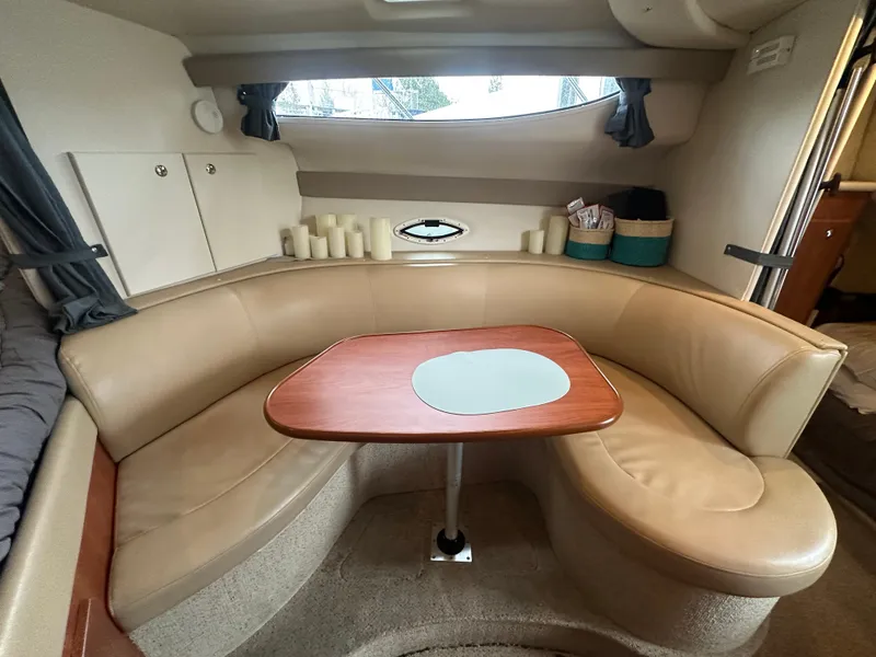 Slide: The Image of 2005 Bayliner 305 interior with beige seating and wooden table in cozy cabin setting. - 28