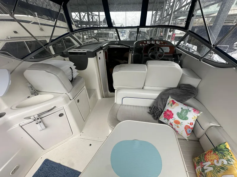 Slide: The Image of 2005 Bayliner 305 boat interior with white seating, colorful cushions, and a steering console. - 32