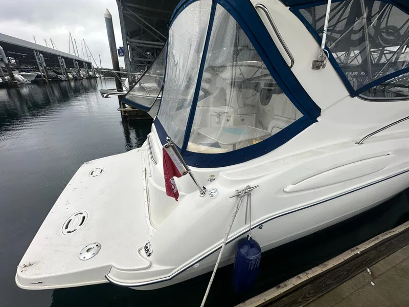 Slide: The Image of 2005 Bayliner 305 boat docked, featuring blue canopy and white hull. - 4