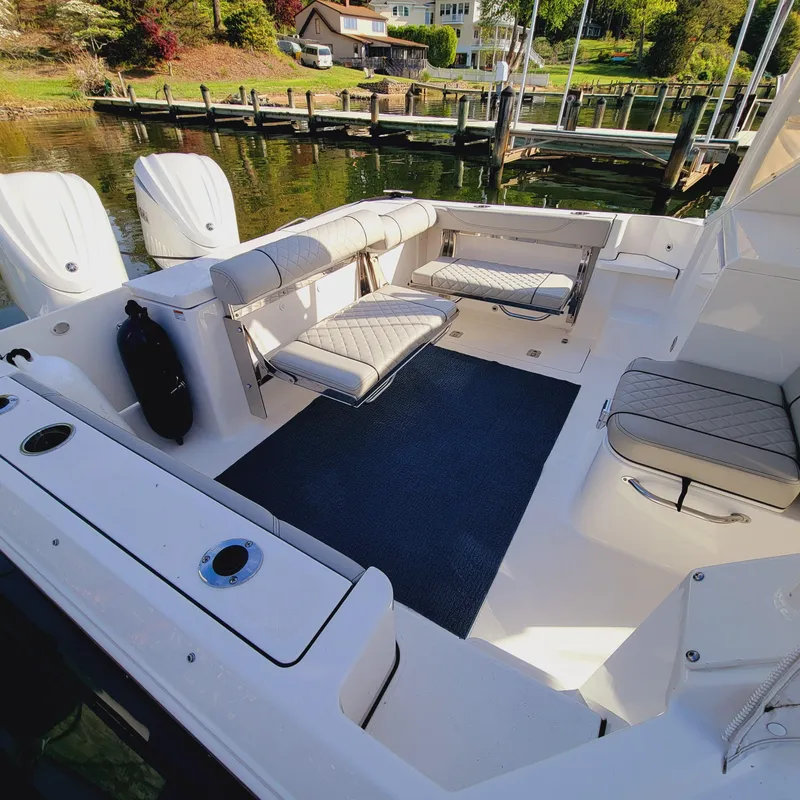 Slide: The Image of 2023 Pursuit OS 325 Offshore boat interior with seating and deck, docked by the water. - 12