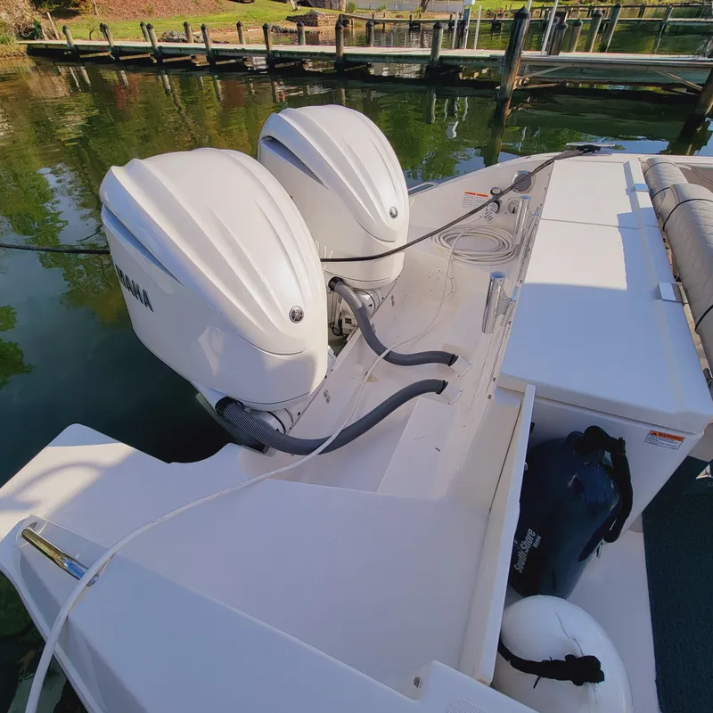Slide: The Image of 2023 Pursuit OS 325 Offshore boat with dual outboard engines docked by the water. - 13