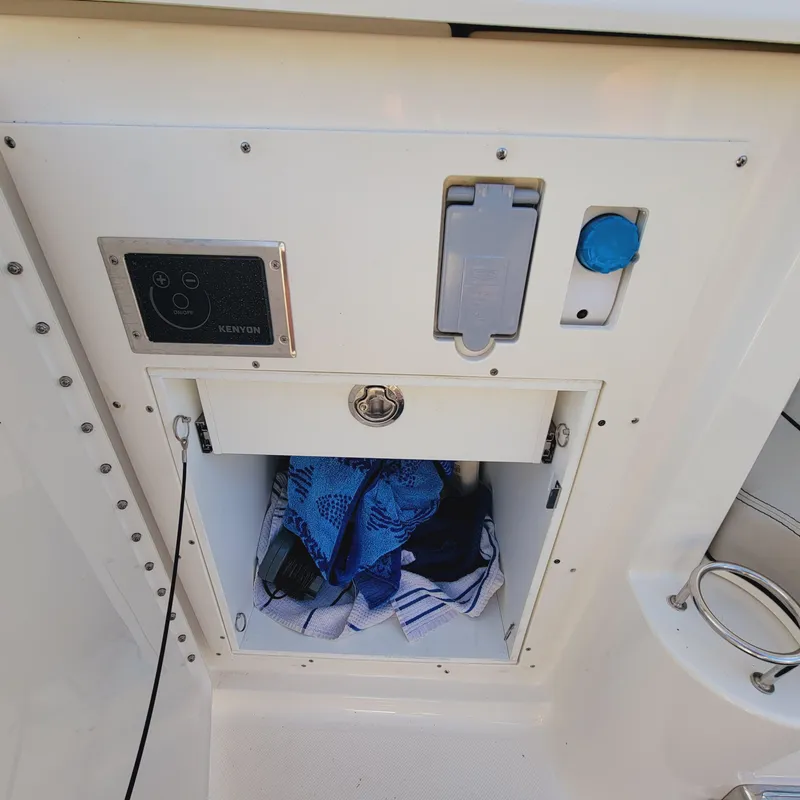 Slide: The Image of Storage compartment on 2023 Pursuit OS 325 Offshore boat with towels and electrical panel. - 20