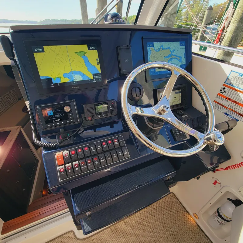 Slide: The Image of 2023 Pursuit OS 325 Offshore helm with navigation screens and steering wheel. - 25