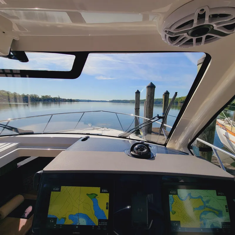 Slide: The Image of 2023 Pursuit OS 325 Offshore boat cockpit with navigation screens, docked by calm waters. - 27