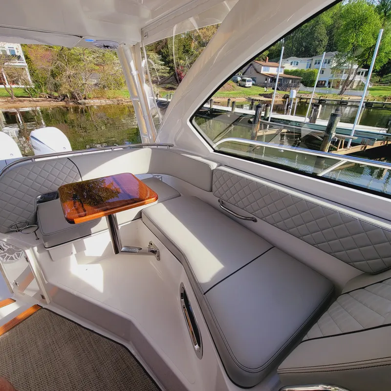 Slide: The Image of 2023 Pursuit OS 325 Offshore boat interior with cushioned seating and wooden table. - 30