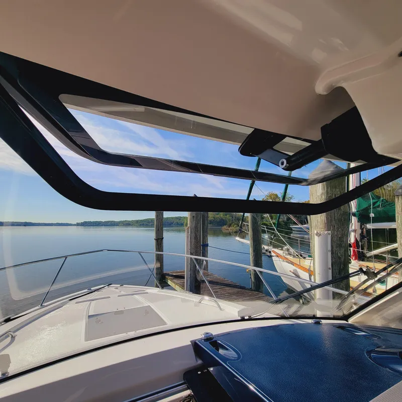 Slide: The Image of 2023 Pursuit OS 325 Offshore boat docked, viewed from interior, overlooking calm waters. - 37