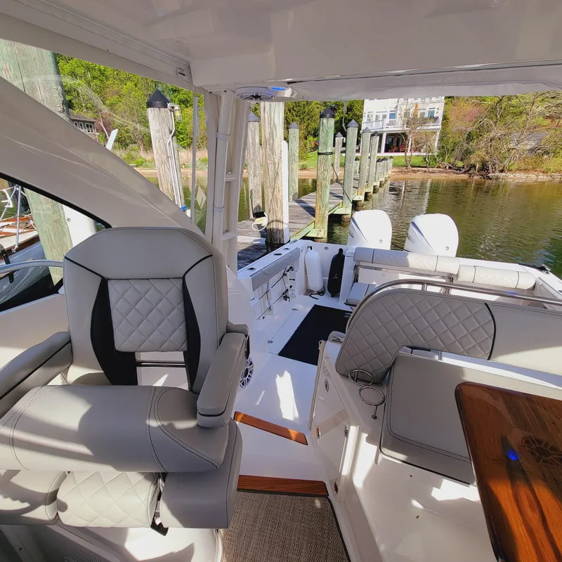 Slide: The Image of 2023 Pursuit OS 325 Offshore boat interior with luxury seating and dock view. - 39