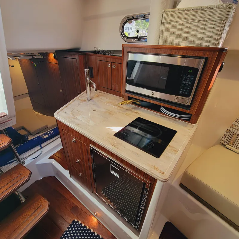 Slide: The Image of 2023 Pursuit OS 325 Offshore yacht interior with kitchenette, featuring microwave and sink. - 42