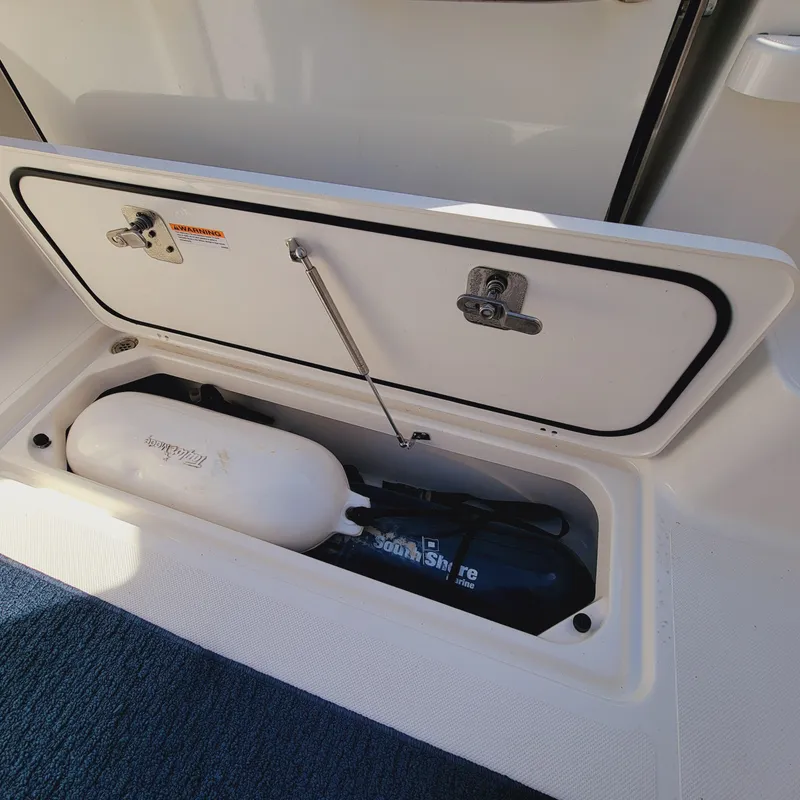 Slide: The Image of Storage compartment on 2023 Pursuit OS 325 Offshore boat, featuring safety equipment. - 47