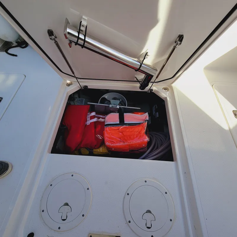 Slide: The Image of Open storage compartment on 2023 Pursuit OS 325 Offshore boat, containing safety gear and equipment. - 48
