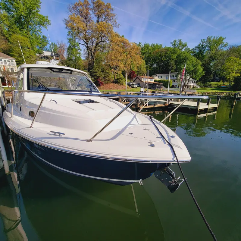Slide: The Image of 2023 Pursuit OS 325 Offshore boat docked in a scenic marina setting. - 6