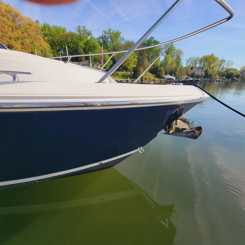 Slide: The Image of 2023 Pursuit OS 325 Offshore boat docked on calm water, surrounded by lush greenery. - 7